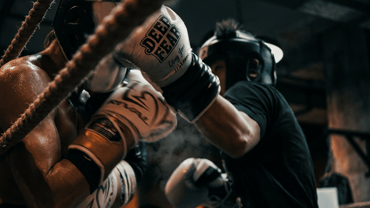 Close-up action shot of boxers sparring in a gritty boxing gym, with Deep Fear boxing gloves in focus. The image conveys intensity, discipline, and fight-ready training energy.